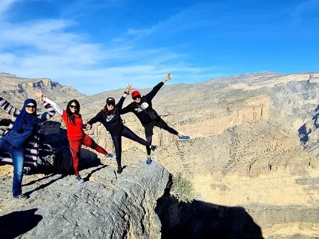 Quattro donne in posa giocosa sul bordo della scogliera con vista sul canyon.