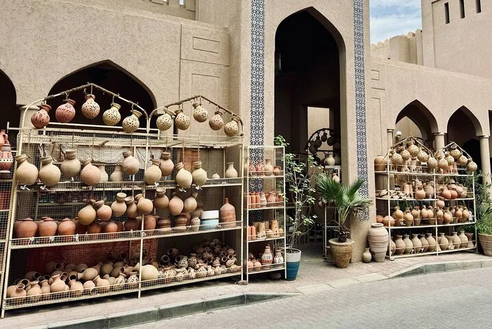 Tontöpfe auf Metallgestellen vor einem traditionellen Gebäude in Oman.