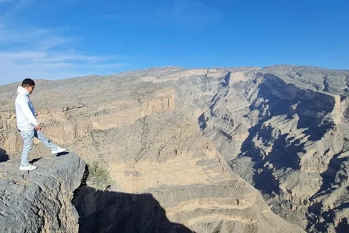 Mann steht am Klippenrand und blickt in einen tiefen felsigen Canyon hinab.
